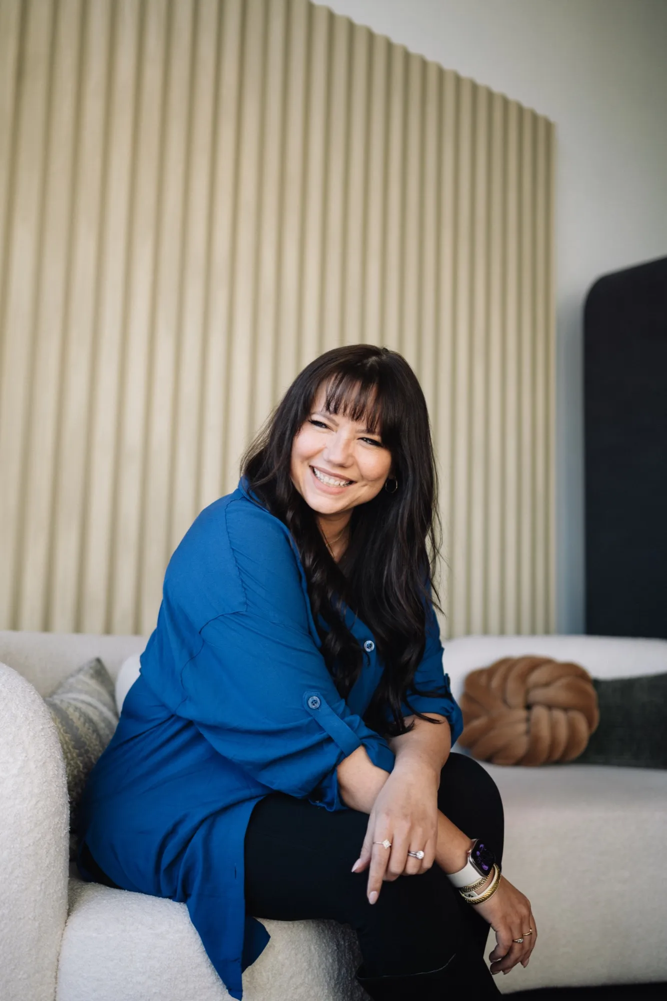 Brooke in a blue shirt on a white couch, relaxed and smiling
