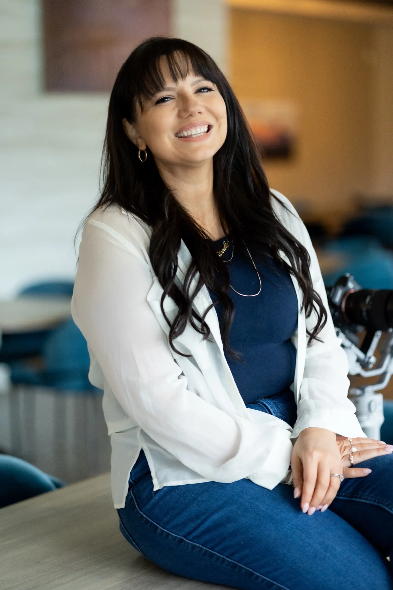Brooke laughing, seated in a white blazer