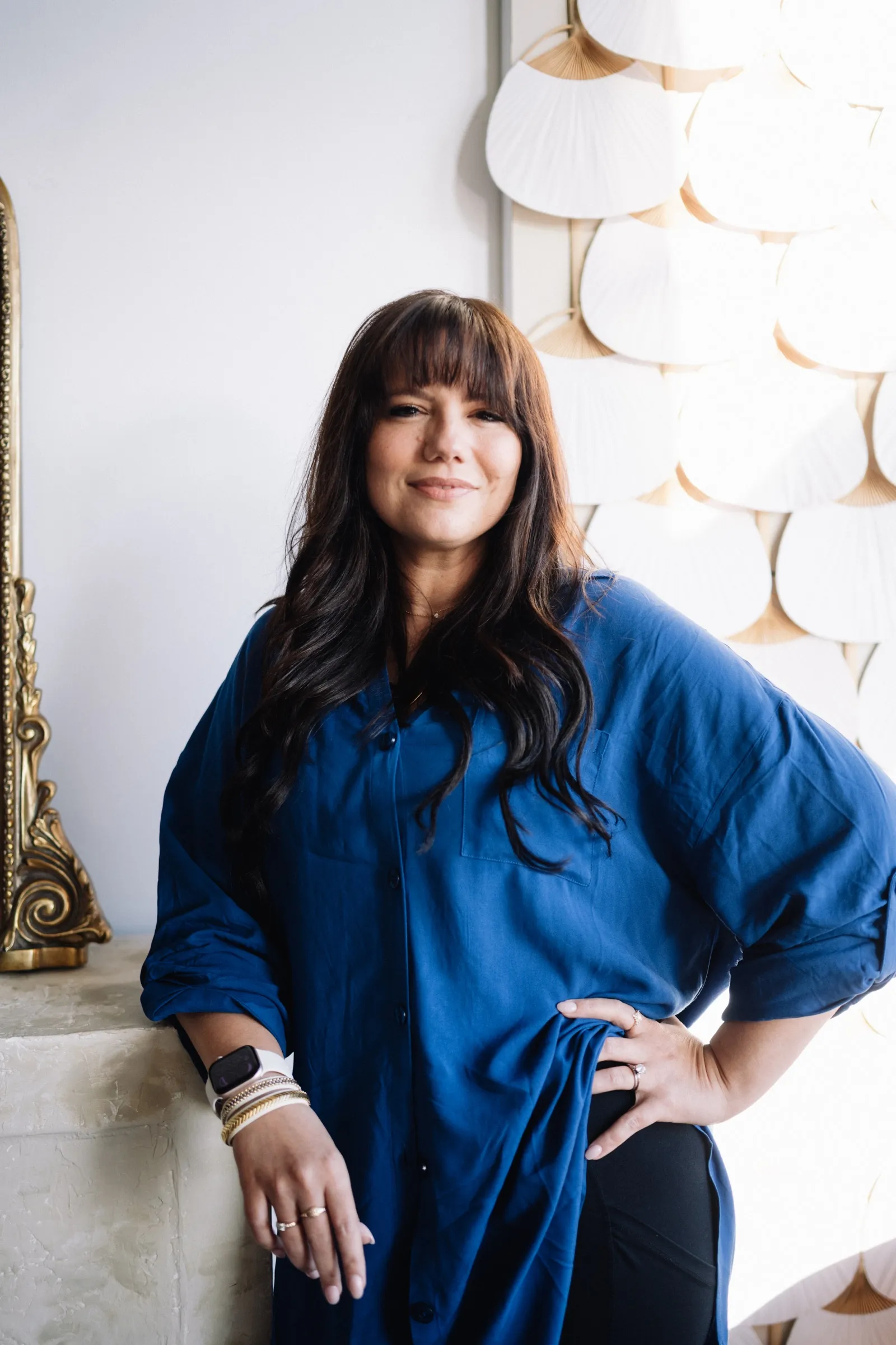 Brooke smiling, one hand on her hip, in a bright studio