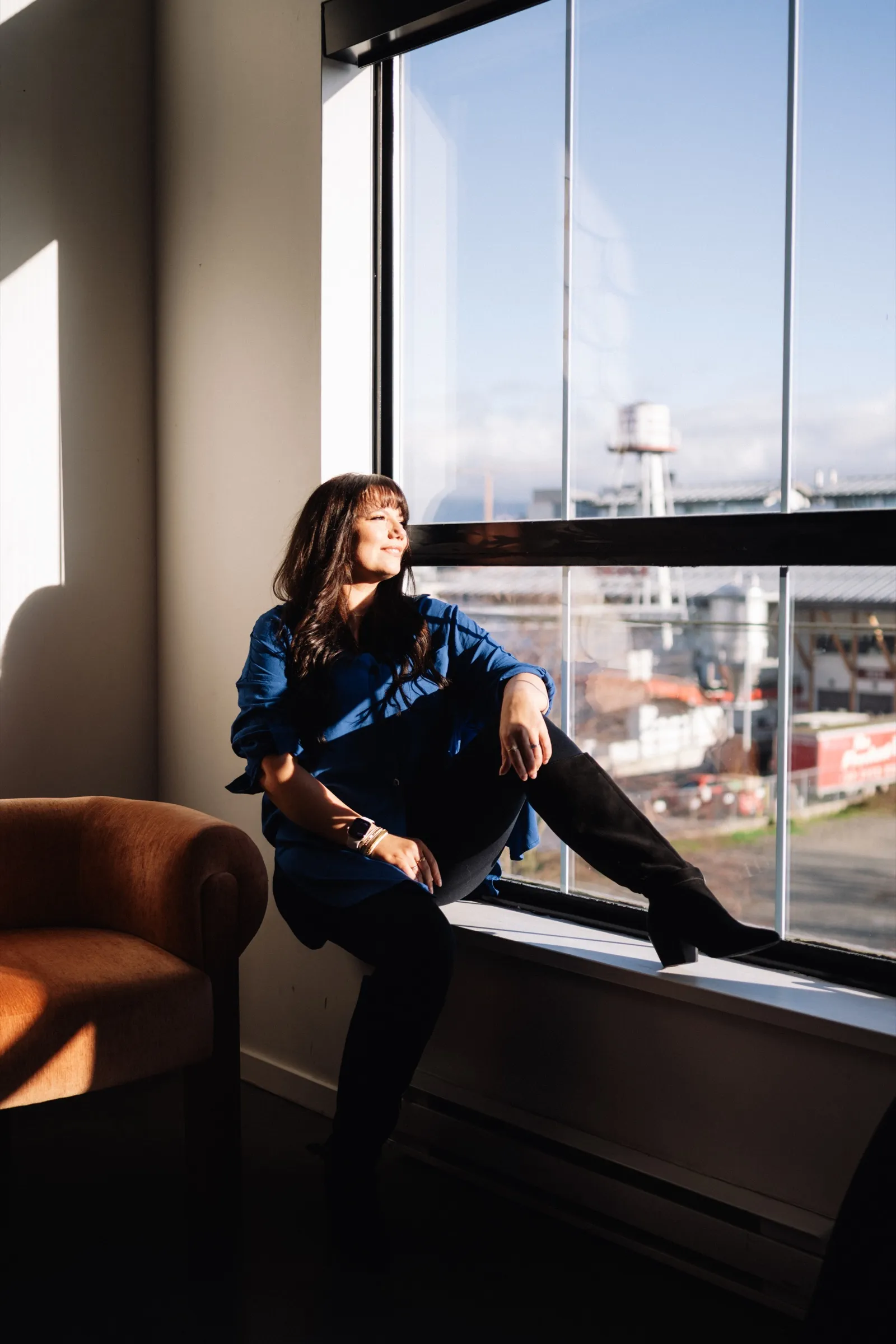 Brooke sitting by a sunlit window, looking out